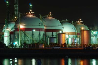 Large silos by river against sky at night