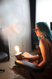 Side view of young woman using phone while sitting on table