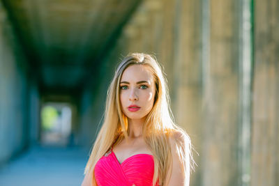 Close-up portrait of beautiful young woman in pink evening dress at colonnade