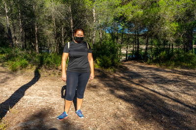 Full length portrait of woman wearing mask standing in forest