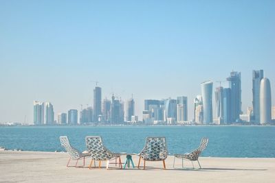 Modern buildings by sea against clear sky