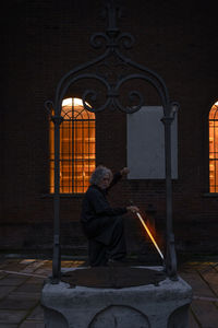 Middle aged tai chi master showing stick exercises outdoors amidst of a medieval cathedral