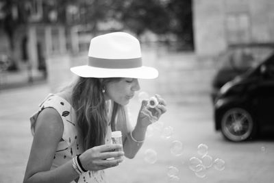 Young woman blowing bubbles on street