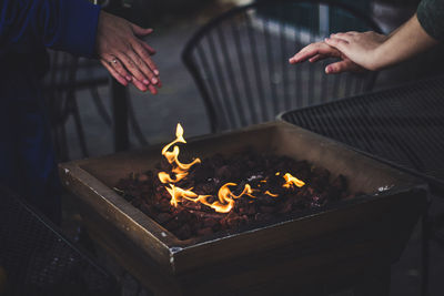 Close-up of people warming themselves by fire