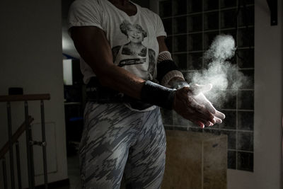 Midsection of man dusting sports chalk at home