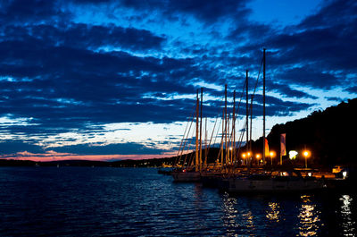 Sailboats in sea against sky at sunset