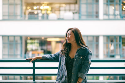 Young woman standing against railing