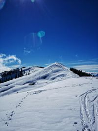 Scenic view of snow covered mountains against blue sky