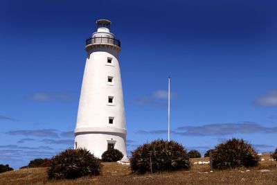 Low angle view of lighthouse by building against sky