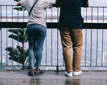 Low section of couple standing against railing