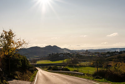 Road leading towards mountains against sky