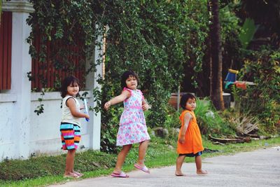 Portrait of sisters walking on road against plants