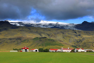 Houses on field by mountain against sky