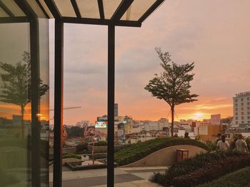 Trees and buildings against sky during sunset