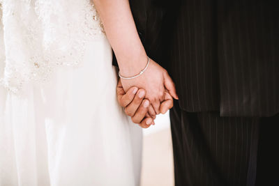 Midsection of couple holding hands