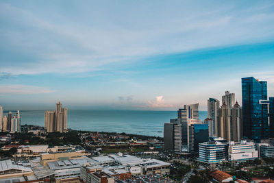 City at waterfront against cloudy sky