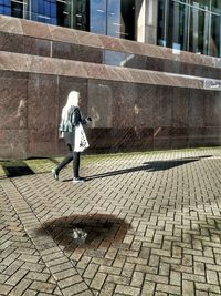Rear view of man walking on footpath