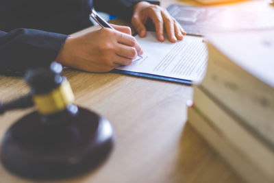 Midsection of female lawyer writing on paper at desk