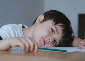  cute boy looking at camera with smiling face while playing with colour pencil, child boy relaxing