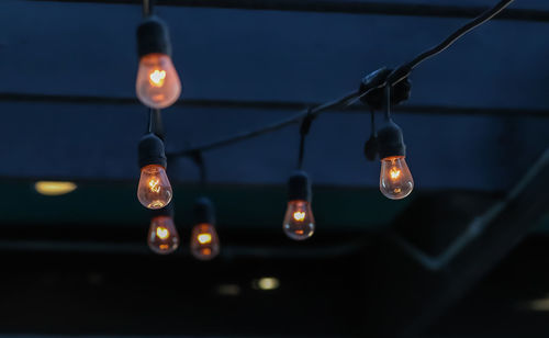 Close-up of light bulb hanging at night