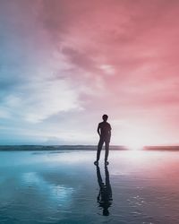 Man standing on beach against sky during sunset