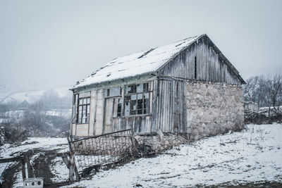 Abandoned house against sky during winter