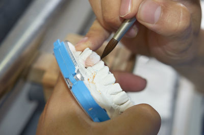 Cropped image of dentist using paintbrush on dentures