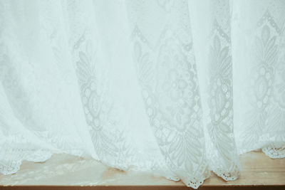 Sunlight shining through white lace window curtains on a breezy day.