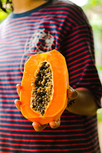 Midsection of woman holding sliced papaya fruit