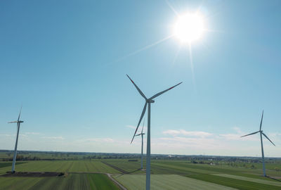 Windmill on field against sky on sunny day