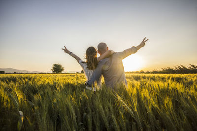 Rear view of couple with gesturing on wheat field