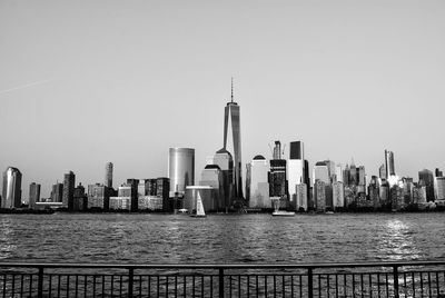 Sea by modern buildings against clear sky