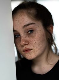 Close-up portrait of young woman with freckles on face