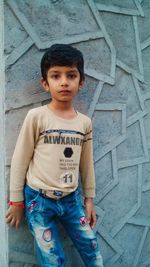 Portrait of boy standing against wall