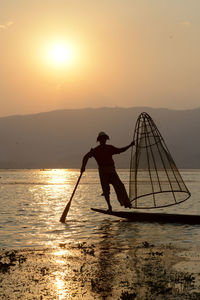 Man fishing in lake at sunset