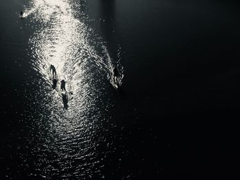 High angle view of silhouette men paddleboarding on sea