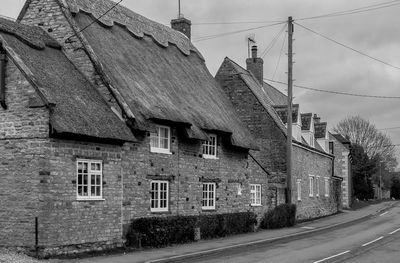 Old houses by road against sky