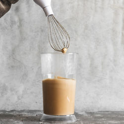 Close-up of hand holding drink on table