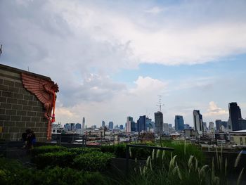 Buildings in city against cloudy sky