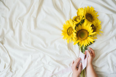 Cropped hands of woman holding flowers on bed