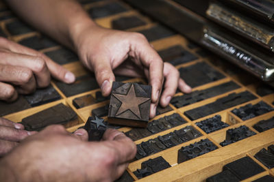 Cropped image of hands holding star shape letterpress at workshop