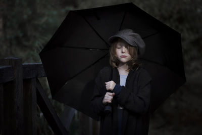 Girl holding umbrella standing in rain during rainy season