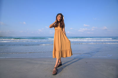 Portrait of woman standing on beach against sky