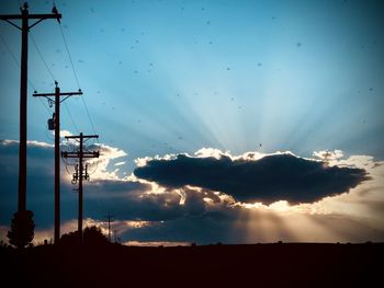 Low angle view of silhouette electricity pylon against sky