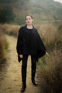 Full length portrait of young woman standing on field