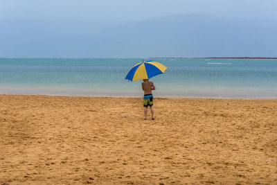 Boy holding sunshade on beach