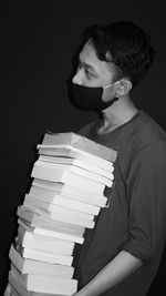 Portrait of young man reading book stack