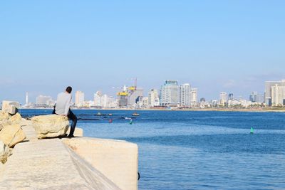 Rear view of woman walking by sea against clear sky