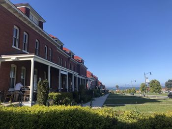 Houses by street against blue sky