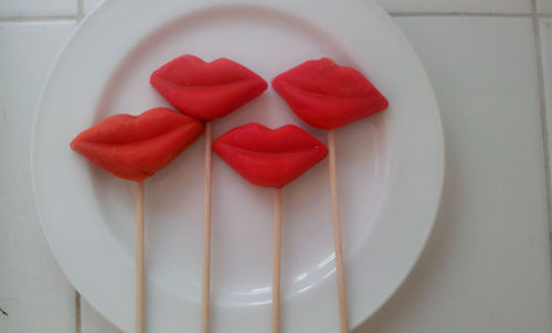 Directly above shot of lip shaped red lollipops on plate